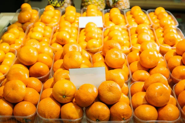 Muitas tangerinas em cestas na prateleira na mercearia. Vitaminas orgânicas na prateleira do supermercado. Dieta, comida vegana, alimentação saudável . — Fotografia de Stock