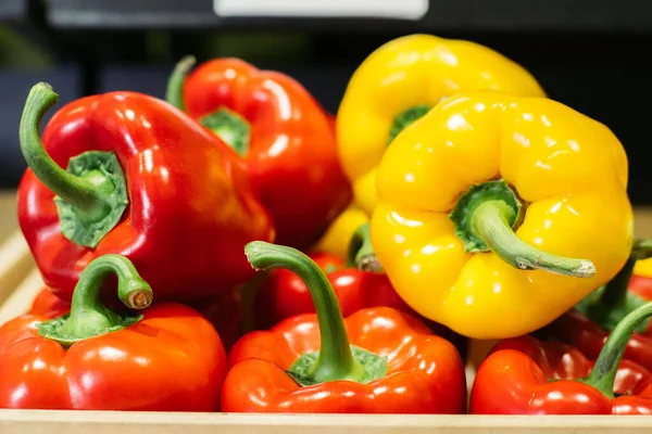 Close-up of red and yellow pepper lying on shelf in grocery. Colorful vegetables for sale in retail shop. Vegan food, healthy eating, bell pepper. Stock Picture