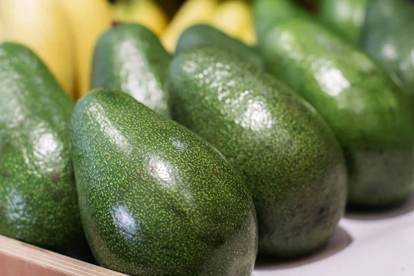 Green avocado on grocery shelf. Close-up of vitamin healthy fruits in supermarket. Fresh organic food, healthy eating, seasonal vitamins. Stock Image