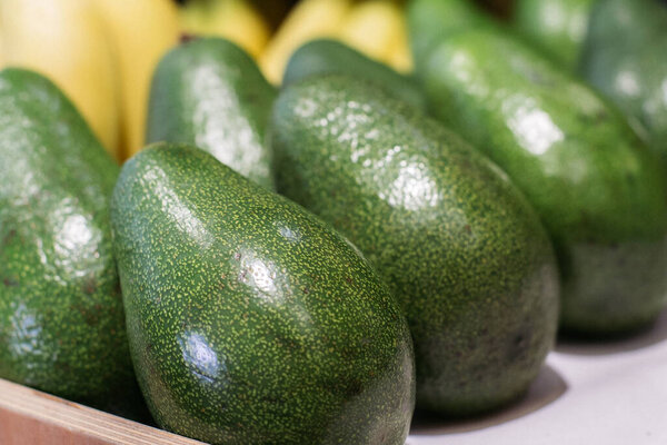 Green avocado on grocery shelf. Close-up of vitamin healthy fruits in supermarket. Fresh organic food, healthy eating, seasonal vitamins. Stock Picture