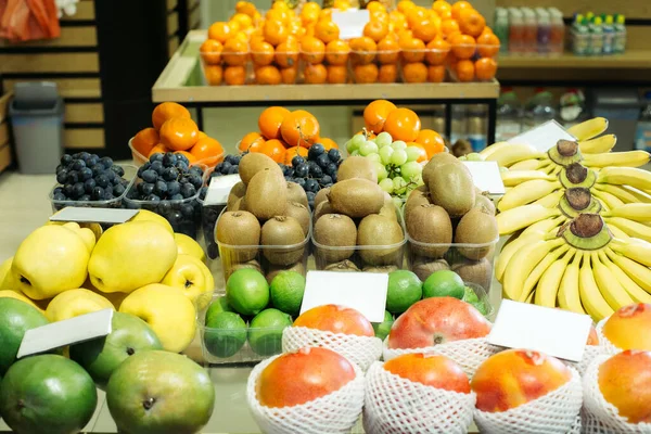 Frutas orgánicas nutricionales en el estante del supermercado. kiwi colorido, plátanos, mandarinas, uvas y limas en la tienda de comestibles. Alimentos saludables, alimentación saludable, dieta, vitaminas . Imágenes De Stock Sin Royalties Gratis