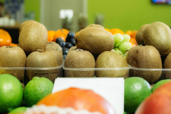 Kiwi fruits in baskets standing on supermarket shelf in grocery. Organic healthful food for sale. Vitamin eating, assortment. Stock Photo