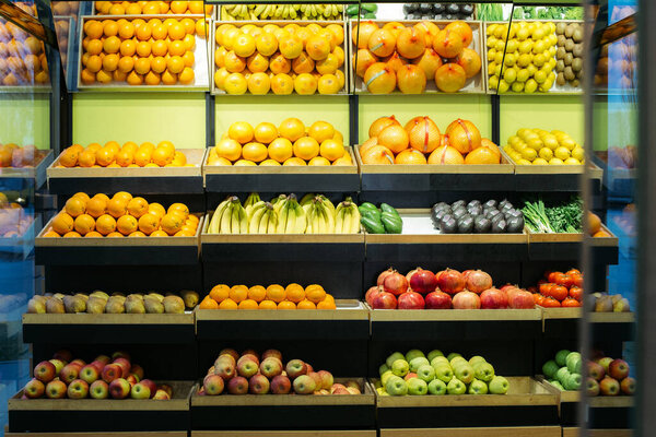 Wide shot of healthful fruits on grocery shelves. Multi-colored apples, pomegranates. tangerines, bananas and avocados in supermarket. Healthy eating, dieting, vitamin food. Royalty Free Stock Photos