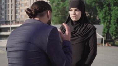 Stresli genç Müslüman kadının portresi, dışarıda kendisine bağıran tanınmayan öfkeli adamı dinliyor. Güzel bir Orta Doğulu eş öfkeli kıskanç kocaya bağırarak bakıyor. Çakışma konsepti.