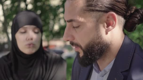 Närbild sida syn på trött skäggig Mellanöstern man suckar som lyssnar på suddig muslimsk kvinna i hijab skällande honom. Upprörd make som har konflikt med sin fru. Skilsmässa, splittring, stress. — Stockvideo