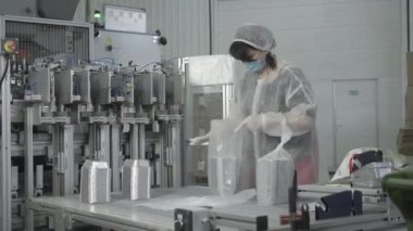 Yüz maskeli kadın, fabrika taşıyıcısında yemek kabı paketliyor. Covid-19 salgınında üretim hattında çalışan konsantre kadın Kafkas işçisinin portresi. Yaşam tarzı, üretim.