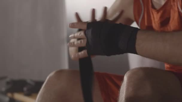 Vit boxare i röd uniform som lindar bandage på handleden. Ung självsäker idrottsman gör sig redo för strid. Kampsport, kampsport, livsstil. Bio 4k ProRes HQ. — Stockvideo