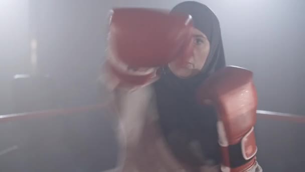 Belle femme musulmane aux yeux bruns combattant l'ombre. Portrait de jeune sportive concentrée frappant à la caméra. Entraînement de boxeuse dans la brume dans le rétroéclairage. Caméra en direct. Siège social Cinema 4k ProRes. — Video