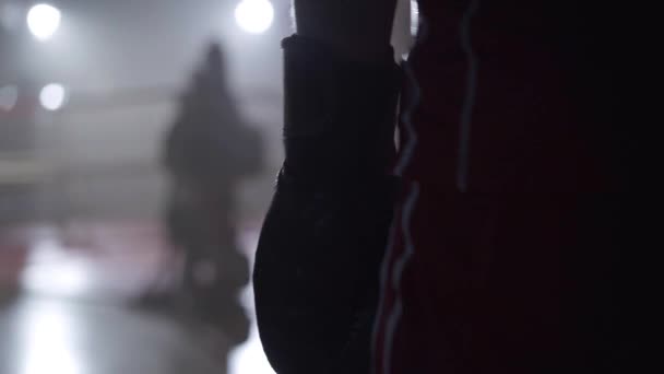 Close-up hand van onherkenbare sporter in bokshandschoenen lopen om te bellen in achtergrondverlichting. Zelfverzekerde kalme blanke bokser nadert te wazig met lense flare. Sport, vechtsport, zelfvertrouwen. — Stockvideo