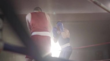 Arka planda boks ringinde dövüşen kendine güvenen genç sporcuların geniş açılı görüntüsü. Güçlü atletik boksörlerin portresi. Lensli dumanlı boksörler. Spor, yaşam tarzı, dövüş sanatları..