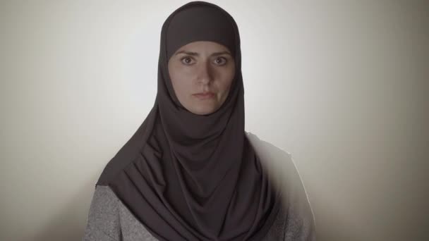 Gros plan de la femme musulmane sérieuse dans le hijab ne montrant aucun geste croisant les mains dans la fusée éclairante. Portrait de jeune femme confiante charmante aux yeux marron niant. Désaccord, mode de vie, rétroéclairage. — Video