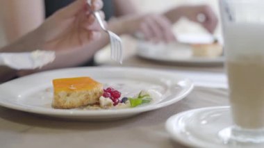 Çatal ve bıçak kullanan beyaz kadın elleri tabaktan dondurmayla tatlıyı alıyor. Restoranda ya da kafede lezzetli tatlılar yiyen tanınmayan bir kadın. Yemek, aşçılık, mutfak, eğlence, yaşam tarzı..