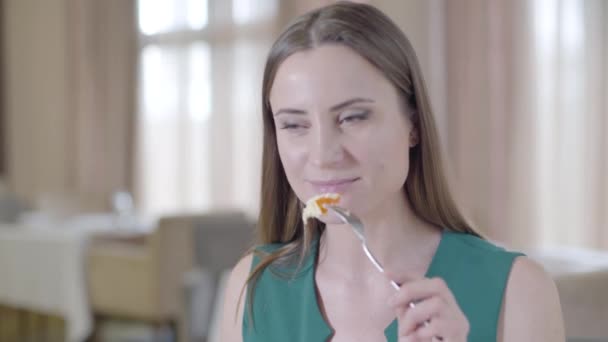 Primer plano de mujer morena disfrutando del postre en el restaurante. Retrato de una joven dama caucásica sonriente con ojos marrones comiendo panadería dulce en la cafetería. Alegría, comida, ocio, estilo de vida . — Vídeos de Stock