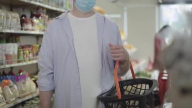 Markette elinde alışveriş sepetiyle duran yüzü tanınmayan bir adam. Yetişkin beyaz erkek alıcı Covid-19 salgınında gıda dükkanında iyi iş yapıyor. Coronavirus yaşam tarzı.