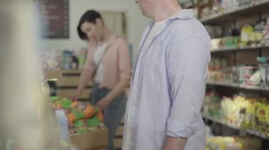 Yiyecek pazarından kurabiye çalan tanınmamış yetişkin bir adam. Kafkasyalı soyguncu ambalajı alıp gidiyor. Arka planda malları seçen kadın. Suç, kanun ihlali, soygun, yaşam tarzı.