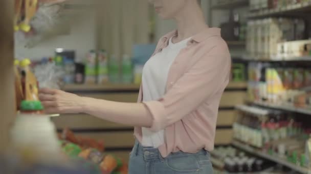 自信的年轻女性买家在超市用智能手机检查产品。一个无法辨认的女人在食品店里扫描商品.在日常生活中使用现代技术. — 图库视频影像