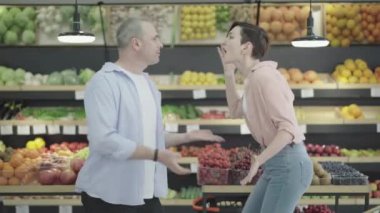 Manavda duygusal olarak tartışan gergin bir erkek ve kadının yan görünüşü. Kafkasyalı bir ailenin yemek dükkanında tartıştığı bir portre. Çatışma, evlilik ve ilişki sorunları, satın alma.