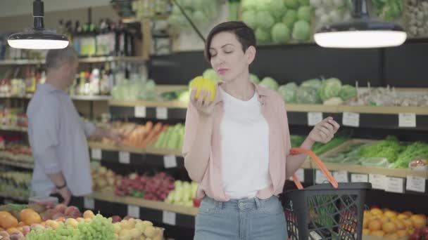 Çekici beyaz bir kadının marketten vejetaryen sebze alırken orta pozu. Süpermarkette dolmalık biber kokusu alan güzel bir kadının portresi. Yaşam tarzı, vejetaryenlik. — Stok video