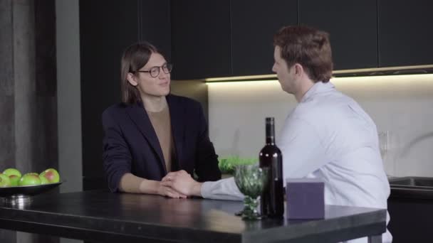 Hombre caucásico adulto tomando la mano de un joven sonriente con gafas. Retrato de una feliz pareja gay casada hablando en la cocina de su casa. Lgbt, relación del mismo sexo, felicidad, estilo de vida . — Vídeos de Stock