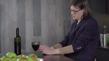 Şişeden şarap içen ve akıllı telefonu kaldıran üzgün ve stresli adamın yan görüntüsü. Gözlüklü genç beyaz adam içki bağımlısı. Depresyon konsepti, alkol kullanımı.