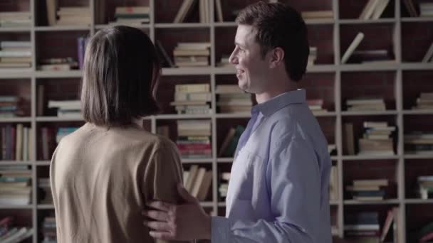 Caucasian gay couple choosing books to read on shelves and hugging. Back view of happy smiling men enjoying weekends together. Lgbt lifestyle, hobby, happiness, intelligence. — Stock Video