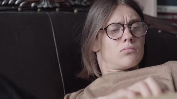 Close-up of focused long-haired brunette guy in eyeglasses reading book. Portrait of concentrated intelligent Caucasian man enjoying literature. Hobby, lifestyle, intelligence, joy. — Stock Video