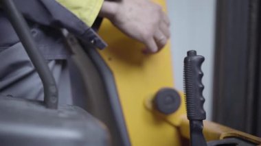 Beyaz bir erkek el, yükleyici kontrol kolunu çeviriyor. Fabrikadaki depoda çalışan tanınmayan profesyonel şoför. İstihdam, iş, meslek, sanayi deposu.