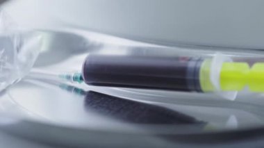 Kanlı şırınganın aşırı yakın çekimi. Tıbbi ekipmanlar hastane laboratuarında yatıyor. Covid-19 salgınında kan testi yapıldı. Coronavirus bilimsel araştırması.