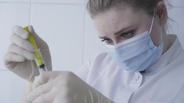 Cara de primer plano del asistente de laboratorio caucásico enfocado procesando la muestra de sangre en el laboratorio. Retrato del médico caucásico concentrado seguro en mascarilla facial trabajando en la pandemia de Covid-19 . — Vídeo de stock