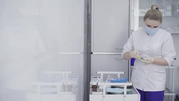 Femme concentrée dans une seringue de remplissage de masque facial avec une solution saline. Portrait d'une infirmière ou d'un médecin caucasien confiant travaillant à l'hôpital pendant la pandémie de Covid-19. Coronavirus traitement, médecine. — Video