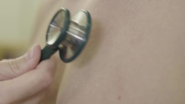Primo piano estremo della mano femminile utilizzando stetoscopio sul busto maschile nudo. Medico caucasico irriconoscibile che esamina il sistema respiratorio dell'uomo in ospedale. Esame medico, malattie cardiovascolari. — Video Stock