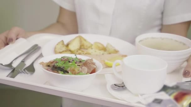 У жіночих руках тацю з лікарняною їжею. Неупізнавана кавказька медсестра в формі зі смачною картоплею, салатом і супом в палаті. Медицина, догляд.. — стокове відео