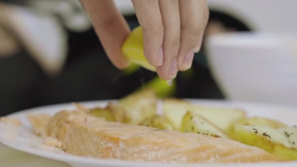 Mão feminina espremendo limão em peixe vermelho. Close-up de paciente feminino irreconhecível comer refeição saborosa nutricional no luxuoso hospital moderno . — Vídeo de Stock