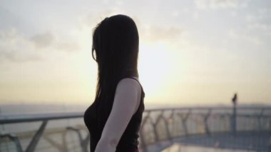 Güneş ışığında dönen zarif esmer kadının orta pozu. Köprüde dans eden zayıf, çekici beyaz balerin. Doğal güzellik, yaşam tarzı, koreografi, kadınlık.