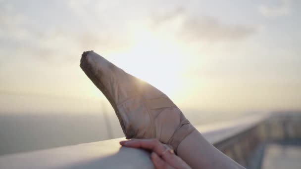 Nahaufnahme eines weiblichen Fußes in Spitzenschuhen mit Sonnenaufgang oder Sonnenuntergang im Hintergrund. Elegante Hand einer kaukasischen Frau, die die Zehenspitzen berührt und geht. Schönheit, Natur, Balletttanz. — Stockvideo