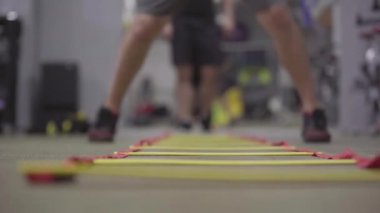 Spor kulübünde hız ve denge antrenmanı yapan tanınmamış sporcular. Beyazların ayakları, spor salonunda yerde merdiven boyunca koşuyor. Sağlıklı spor yaşam tarzı, egzersiz, spor.