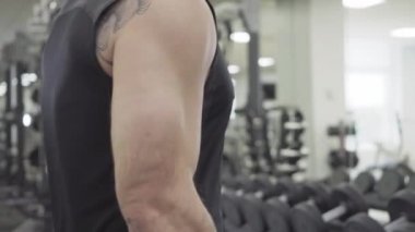 Beden eğitiminde el ağırlığı kaldıran, tanınmayan beyaz bir adamın yan görünüşü. Kaslı erkek koluna yakın çekim. Ağırlık kaldırmada sporcu eğitimi. Vücut geliştirme, sağlıklı yaşam tarzı.
