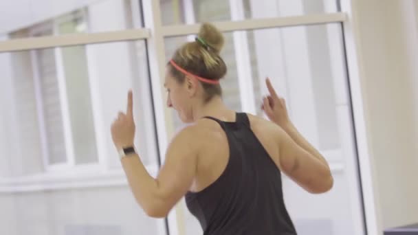 Vista posterior de mujeres entrenadoras activas entrenando a personas en el gimnasio. Cámara en vivo sigue el movimiento de la confiada deportista caucásica haciendo pilates o ejercicios de fitness en el club deportivo. Entrenamiento, deporte . — Vídeos de Stock