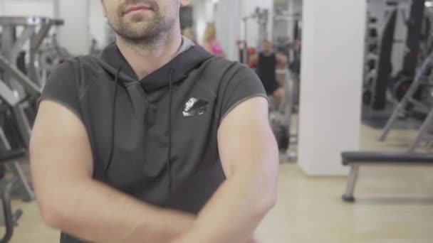 Sportif caucasien barbu méconnaissable croisant les mains comme debout dans la salle de gym. Portrait de l'homme fort confiant posant dans un club de sport à l'intérieur. Masculinité, force, confiance, sport. — Video