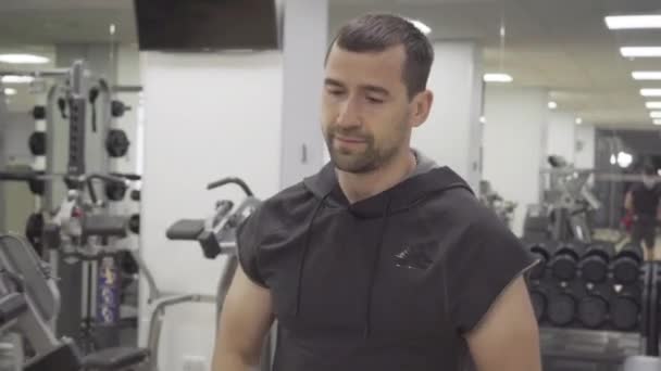 Cansado pero satisfecho deportista caminando en el gimnasio. Retrato de un joven musculoso caucásico paseando en un club deportivo. Estilo de vida deportivo, masculinidad, deporte . — Vídeo de stock