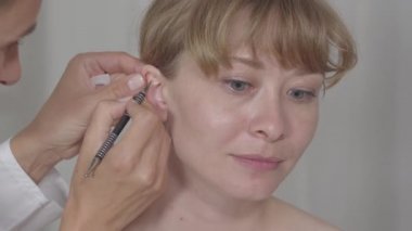 Genç Asyalı kadının kulağındaki akupunkturcu kontrol noktalarına yakın çekim. Auriculoacupunture işlemi. Alternatif tıp, akupunktur, sağlık hizmetleri.