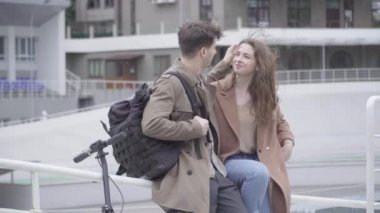 Sokakta dikilip sohbet eden gündelik kıyafetli genç bir çift. Esmer güzel beyaz kadın portresi ve rüzgarlı bir günde dışarı çıkan yakışıklı adam. Aşk konsepti.