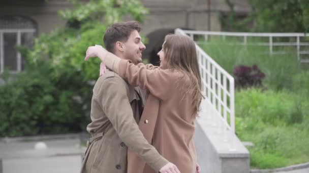 Jonge gelukkige liefdevolle koppel ontmoeting in de stad straat. Portret van een glimlachende blanke man die buiten een vriendin knuffelt en ronddraait. Liefde, geluk, romantiek, afspraakjes. — Stockvideo