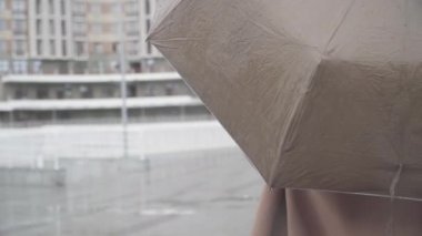 Tanımlanamayan Kafkasyalı kızın yağmuru eliyle kontrol edişinin arka plan görüntüsü. Şehir caddesinde şemsiyeyle dikilen genç bir kadın. Yağmur mevsimi, hava.