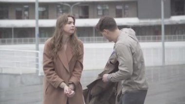 Sevgilisini yağmurluklardan koruyan kendine güveni tam bir sevgili. Güzel esmer beyaz kız arkadaşı sarılıyor ve gülümsüyor. Yağmurlu bir günde dışarıda flört eden kaygısız çift..