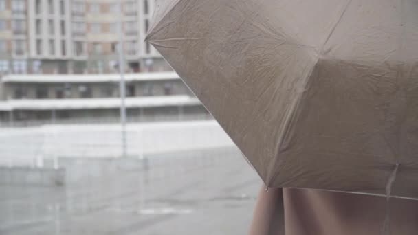 Vista posterior primer plano de irreconocible chica caucásica revisando la lluvia con la mano. Mujer joven de pie con paraguas al aire libre en la calle urbana de la ciudad. Temporada de lluvias, tiempo . — Vídeos de Stock