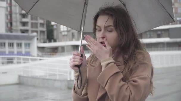 Jeune femme caucasienne malade couché comme debout à l'extérieur sous la pluie et l'attente. Portrait de fille brune ayant le rhume et la grippe. Concept de problèmes médicaux, soins de santé, Covid-19. — Video