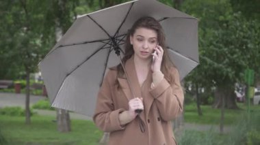 Stresli genç bir kadın yağmurlu bir günde dışarıda telefonu kapatıyor. Kafkasyalı güzel bir kadının iletişim sorunu olan portresi..