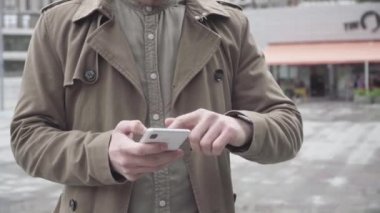 Akıllı telefondan yazı yazan ve ekranı aralayan tanınmamış genç bir adam. Konsantre olmuş Kafkasyalı işadamı şehir caddesinde duruyor ve internette sörf yapıyor. Aygıt bağımlılığı, yaşam tarzı.