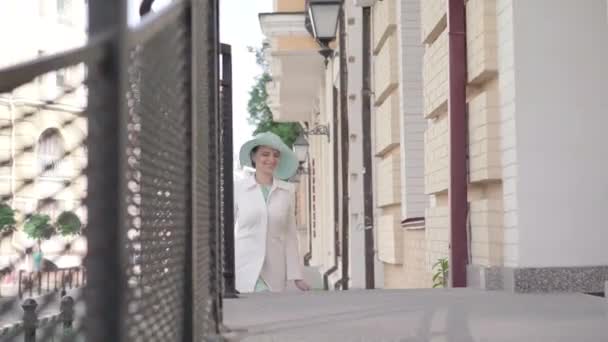 Encantadora mujer alegre subiendo las escaleras y entrando al edificio de la ciudad. Retrato de hermosa dama caucásica en vestido elegante, abrigo y sombrero que va de compras en la ciudad extranjera. Turismo. viajes . — Vídeo de stock